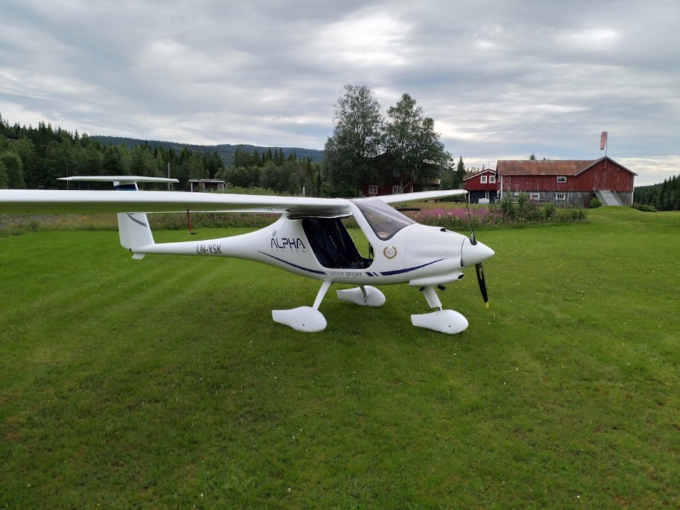 A small white airplane on a grass fieldDescription automatically generated
