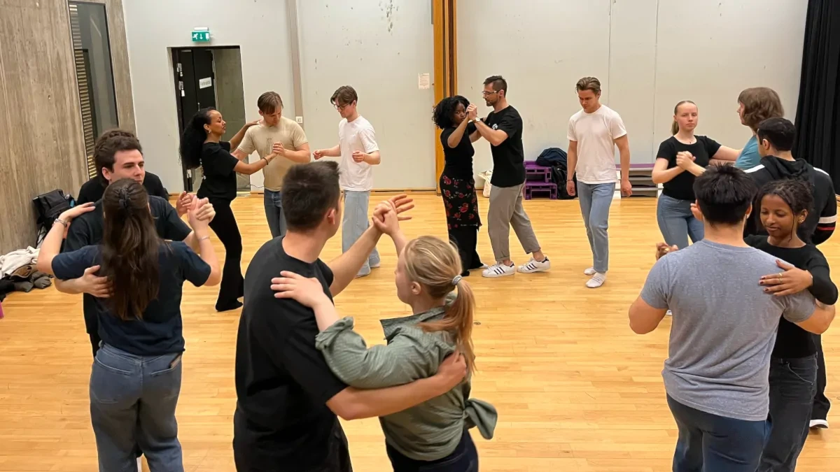 Salsakurs deltakere står i par og øver på salsa-trinn i en stor sirkel