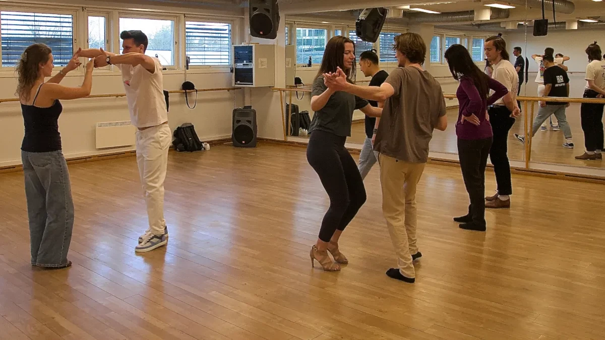 Studenter og voksne øver på dansekurs i bachata