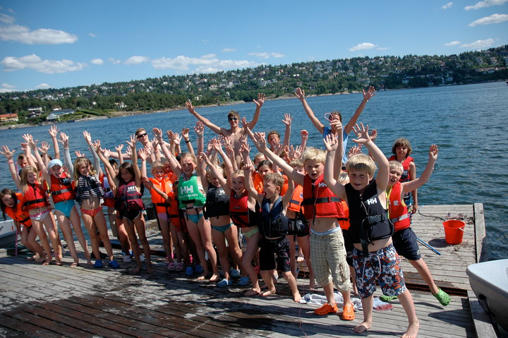Barn som jubler på bryggen med hendene over hodet